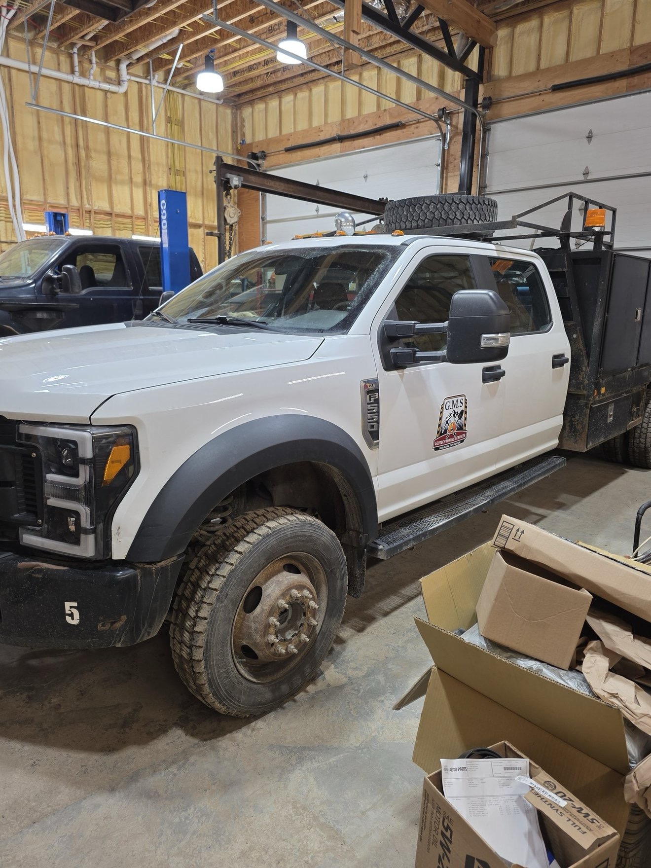White branded work truck parked beside equipment.
