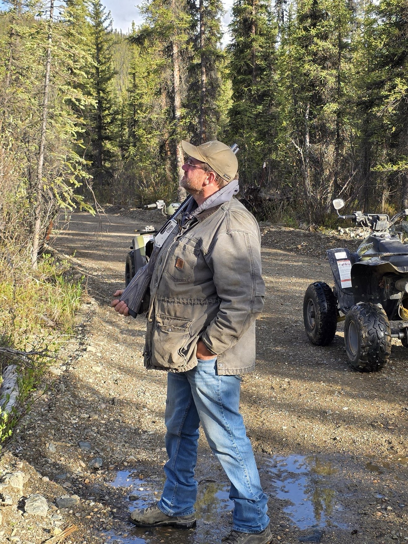 Portrait of a crew member standing near an ATV at camp.