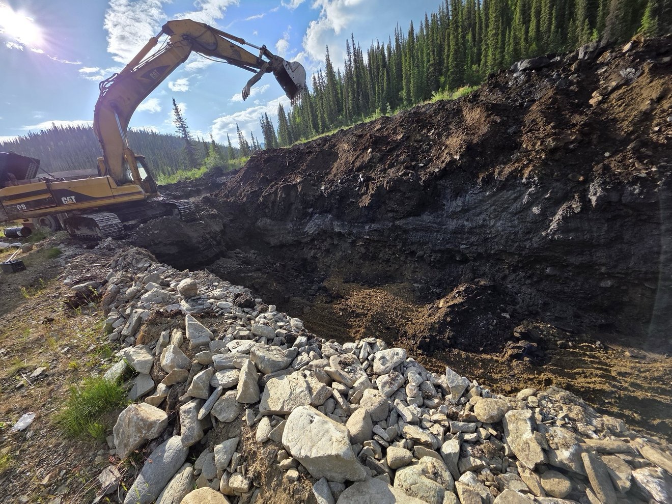 Excavator cutting into a trench on the surface claim.