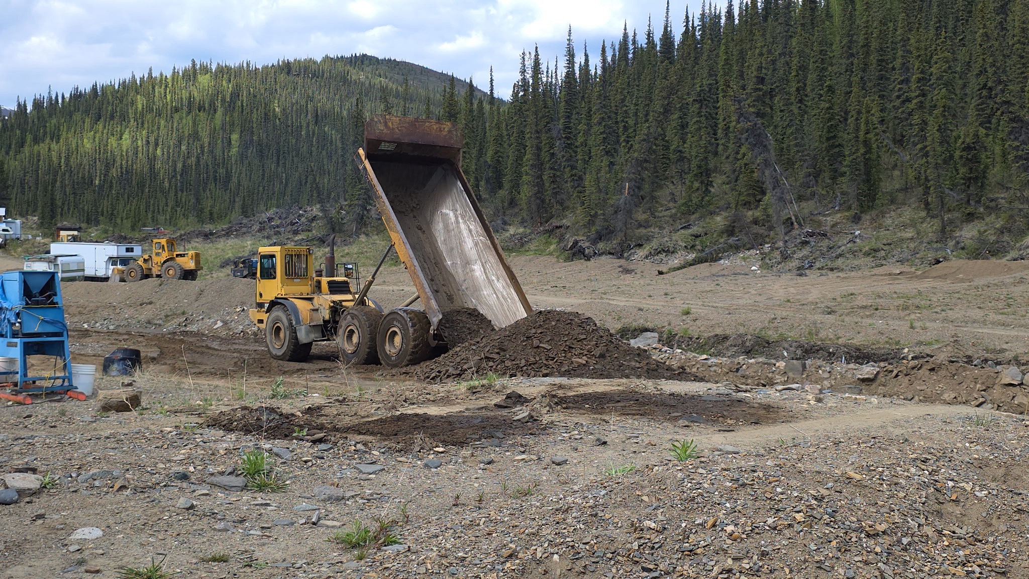 Excavator working beside a truck on the claim.