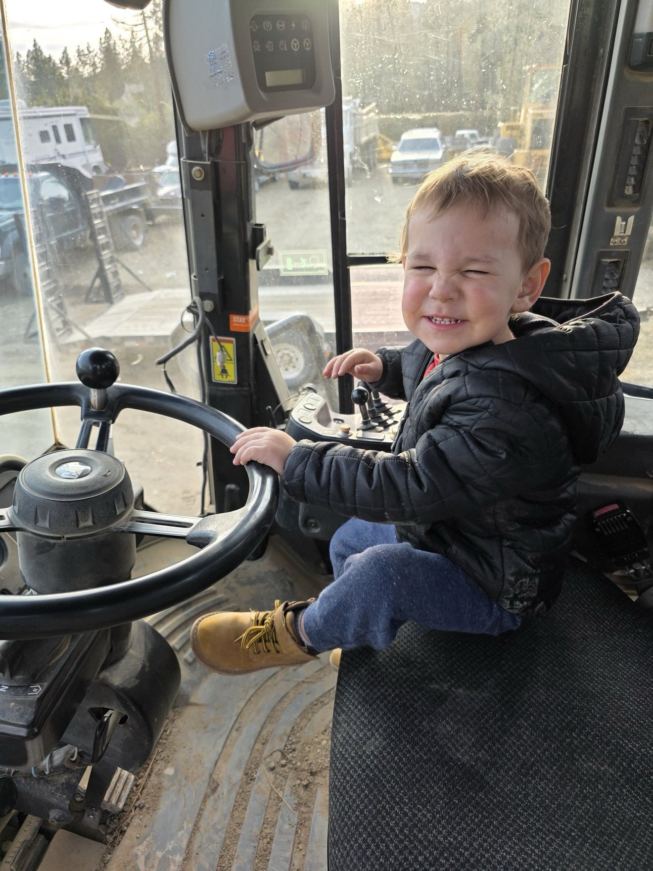 Young child sitting in the cab of heavy equipment.