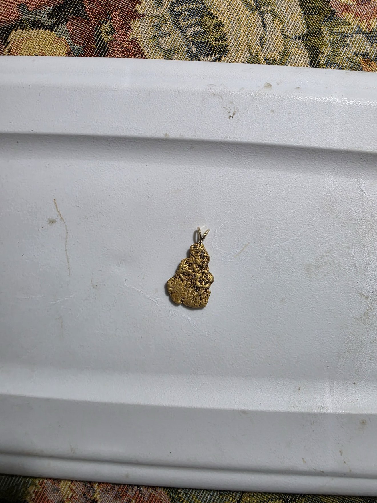 Single gold nugget shown against a white surface.