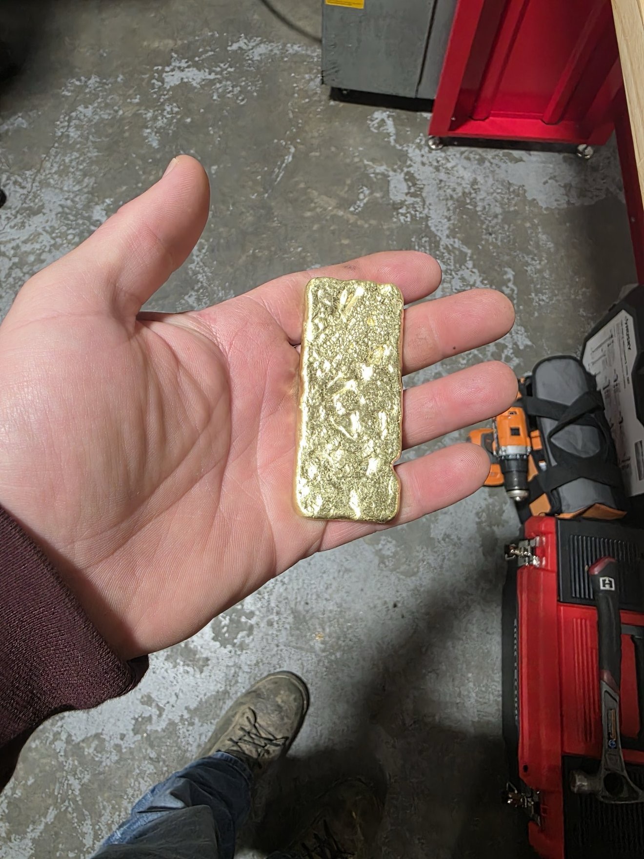 Hand holding a rectangular gold bar.