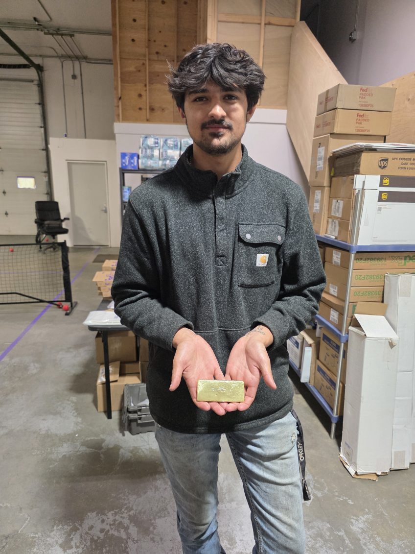 Man holding a gold bar indoors.