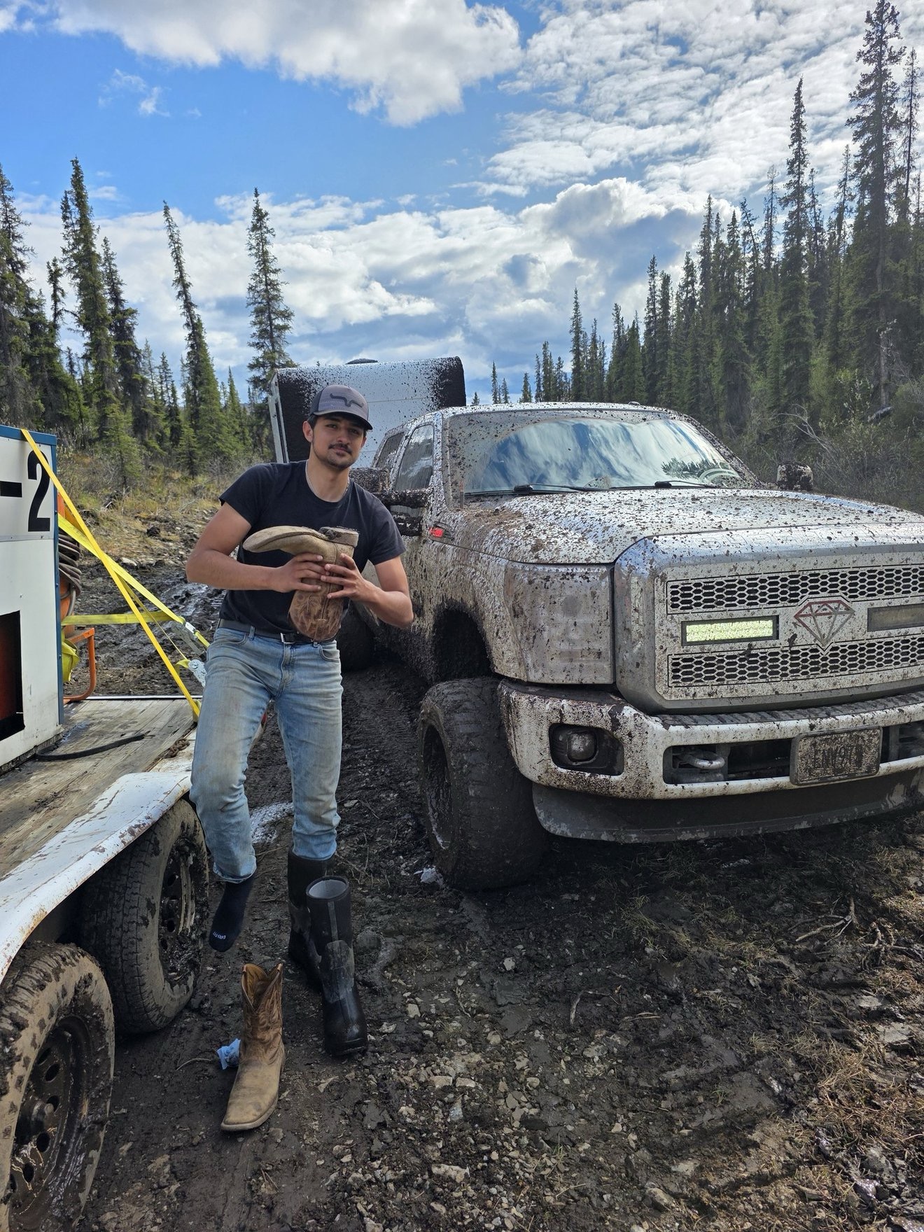 Crew member standing beside a mud-covered work truck.