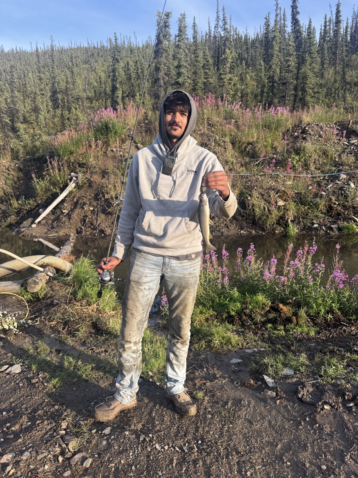 Crew member holding up a gold sample outdoors.