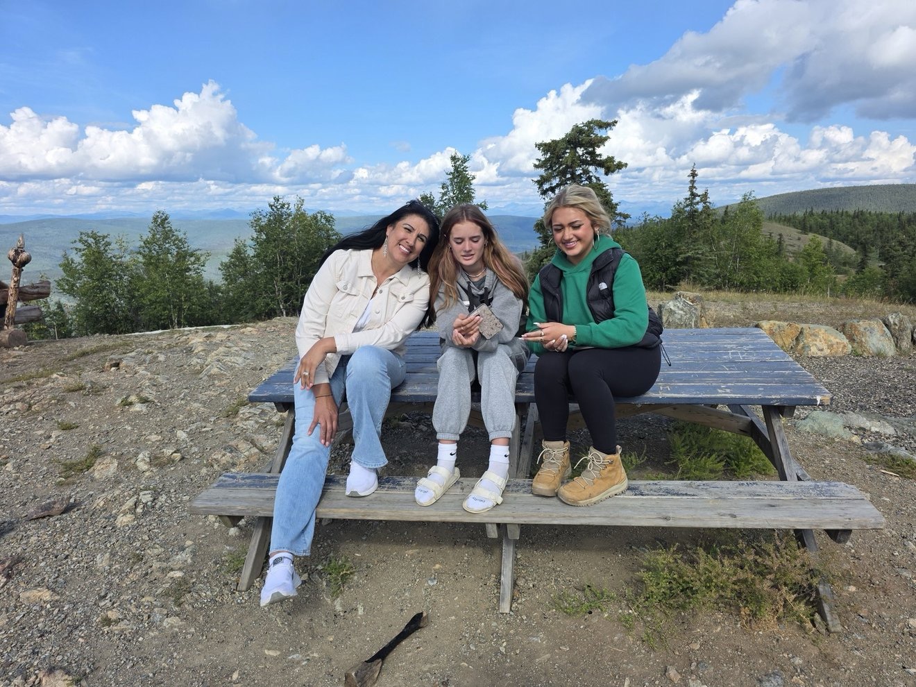 Group portrait at a picnic bench with mountain views.