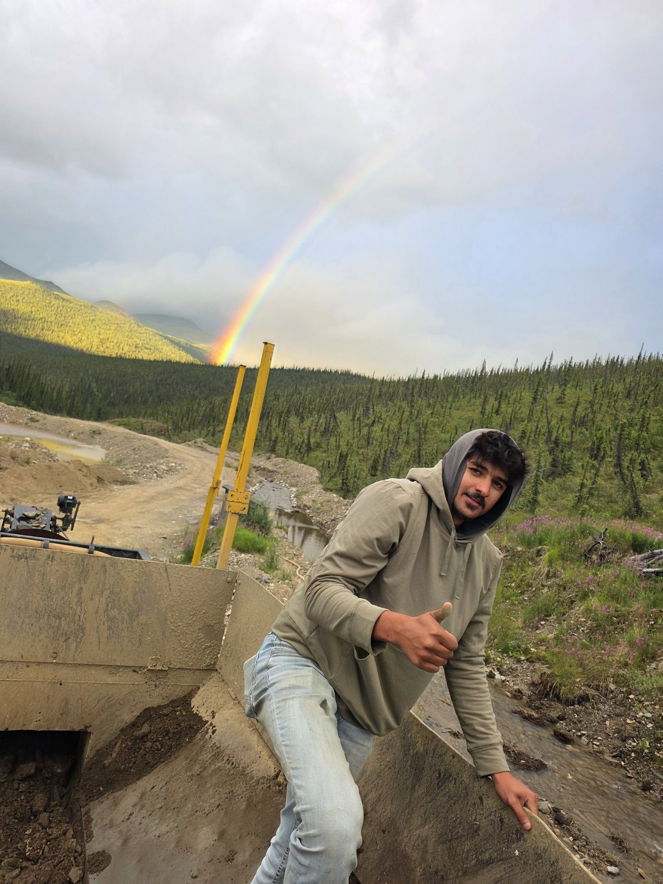 Crew portrait at camp with a rainbow in the background.