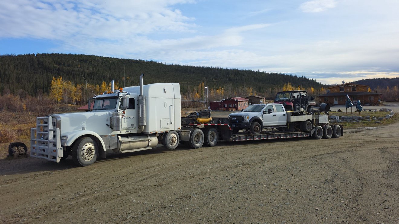 Semi truck and support vehicles parked near camp.