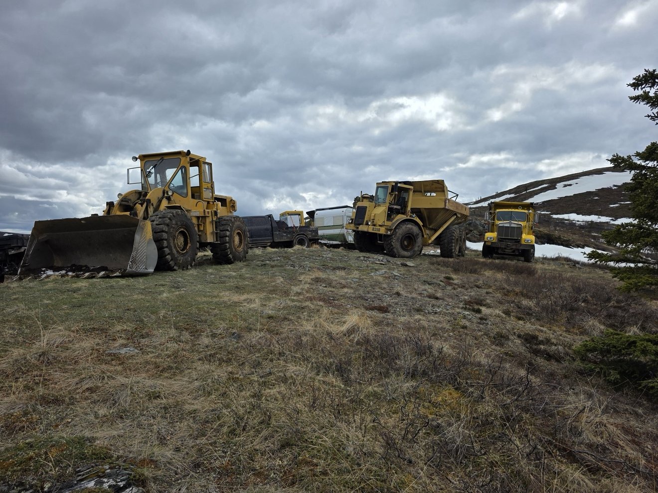 Surface equipment lined up on the claim under cloudy skies.