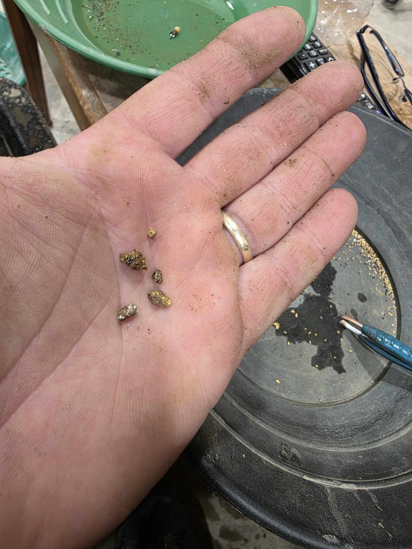 Small gold pieces shown in a hand over recovery equipment.