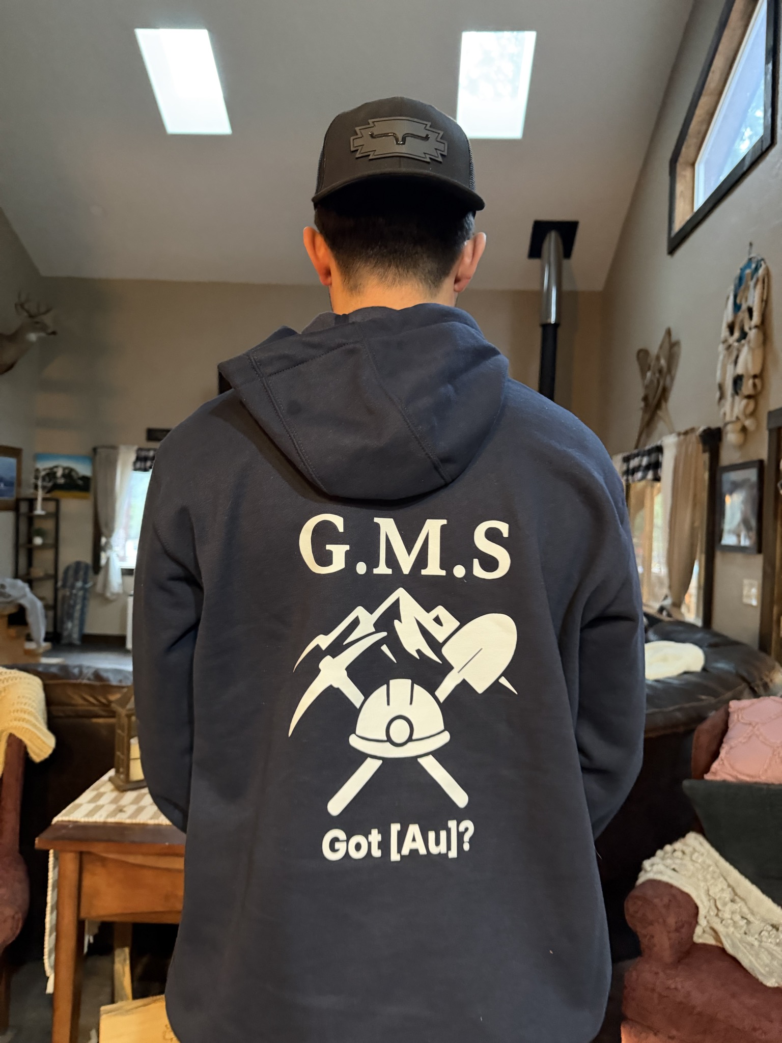 Back view of a GMS Mining hoodie and logo hat being worn.